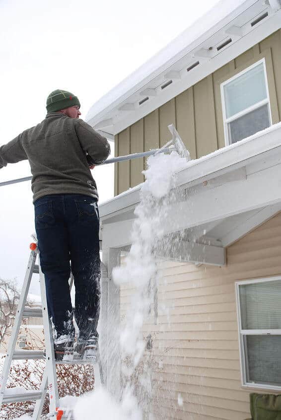 a person brushing snow off their roof