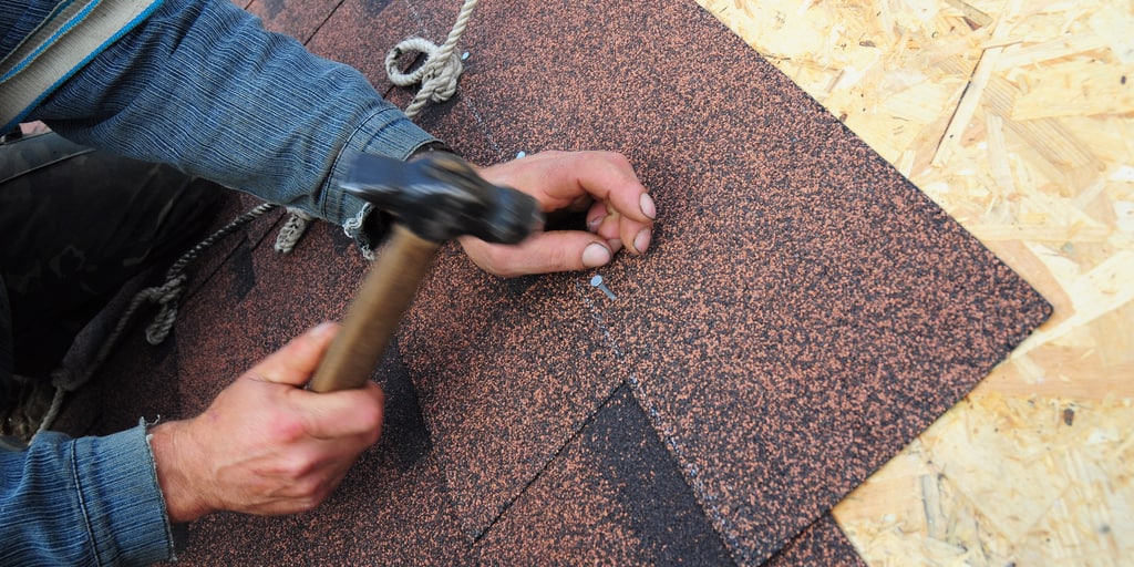 a worker nailing shingles onto a roof