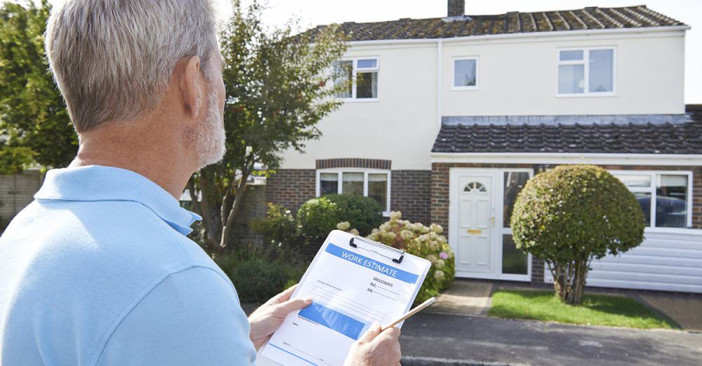 a person with a work estimate form looking at a house